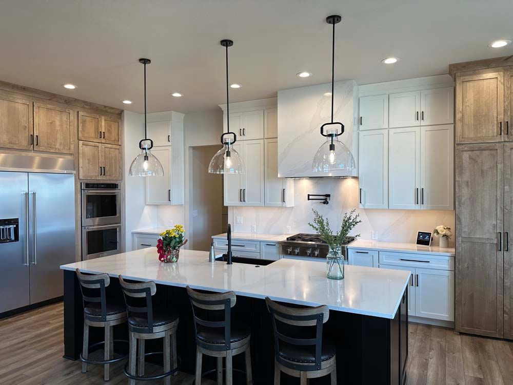 A kitchen with white cabinets , stainless steel appliances , and a large island.