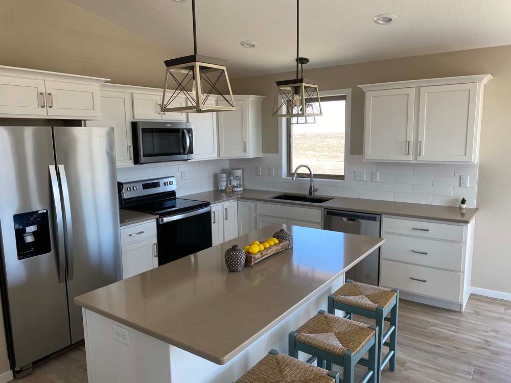 A kitchen with white cabinets , stainless steel appliances , and a large island.