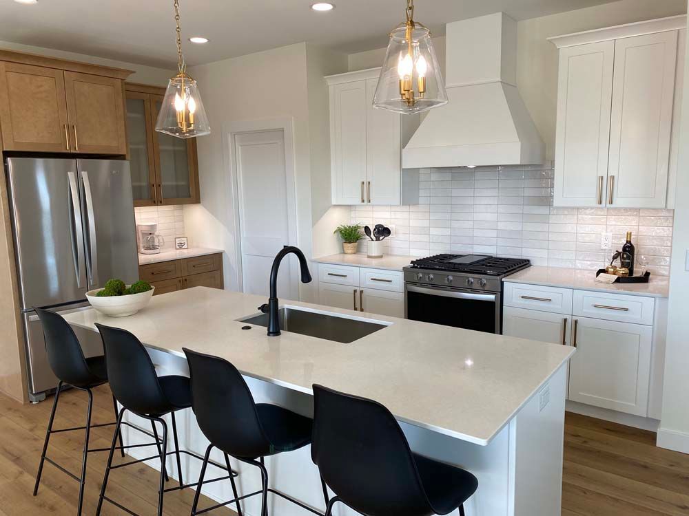 A kitchen with white cabinets , stainless steel appliances , and a large island.