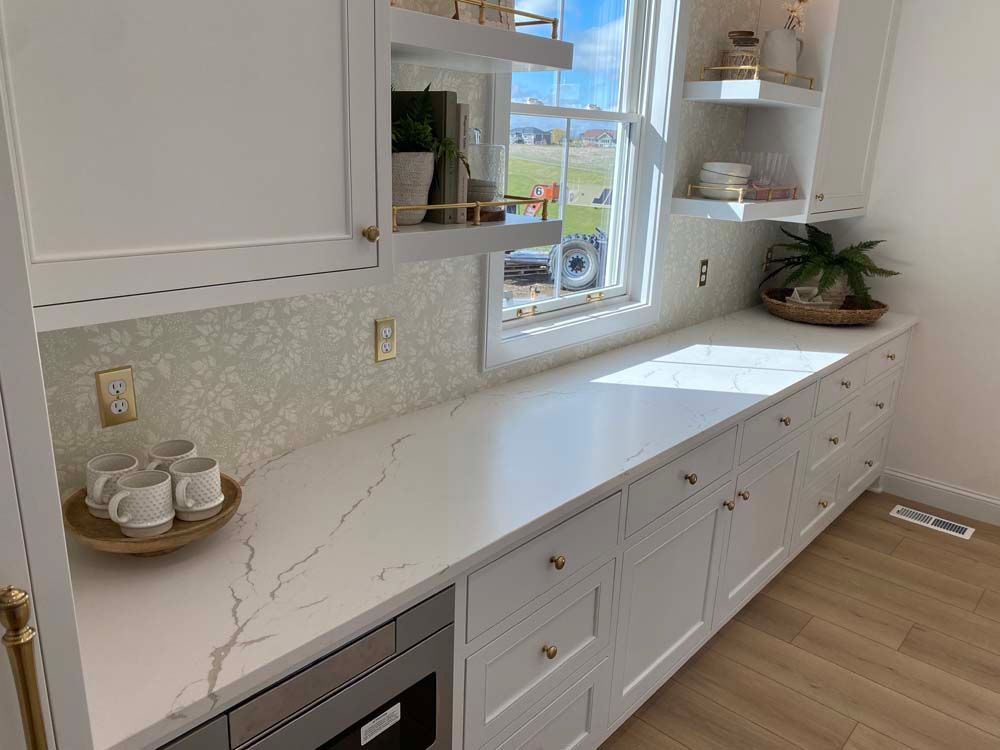 A kitchen with white cabinets , white counter tops , stainless steel appliances and a window.