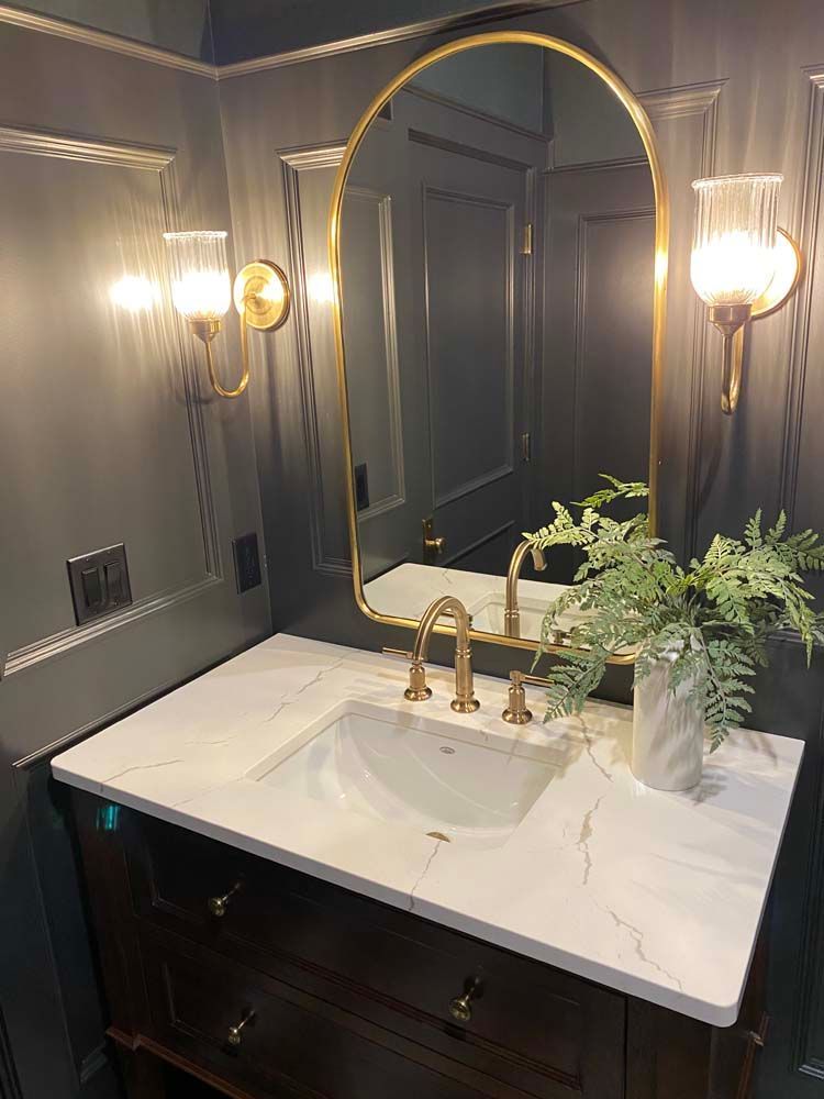 A bathroom with a sink , mirror and lights.