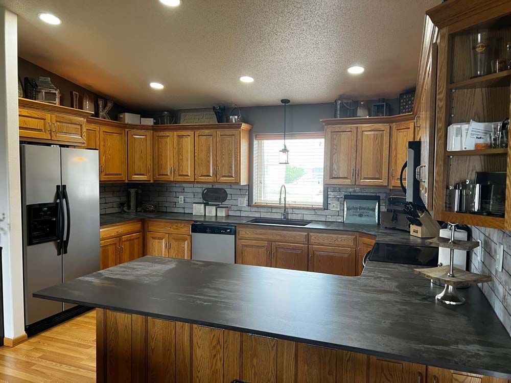 A kitchen with wooden cabinets and a black counter top