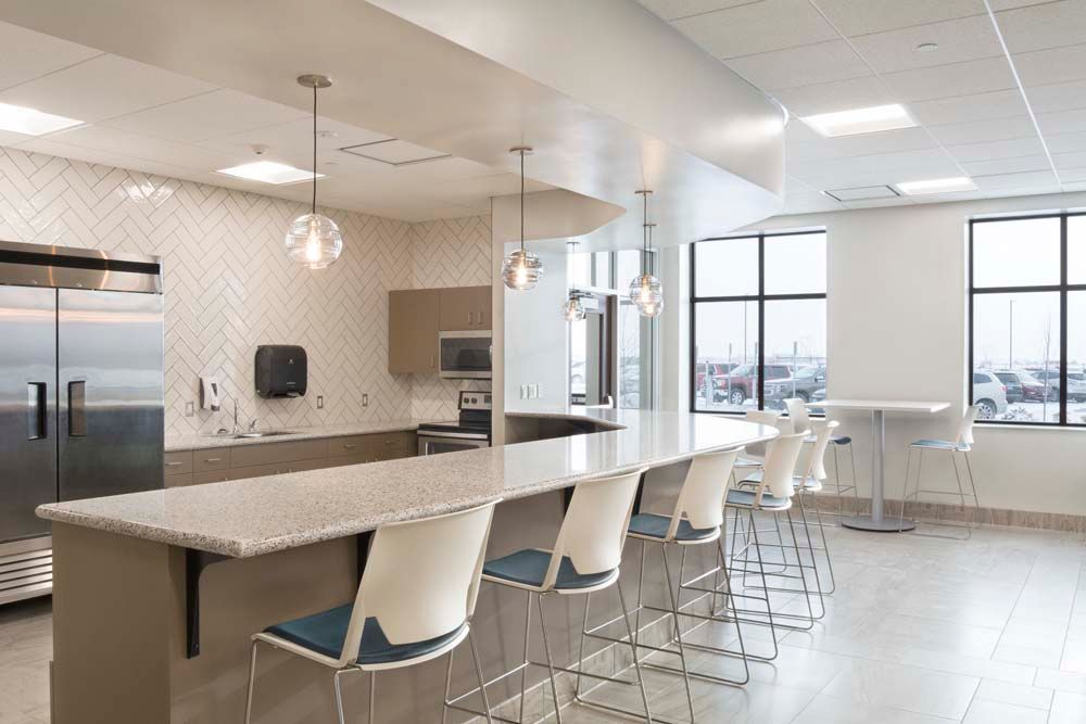 A kitchen with a long counter and a lot of chairs.