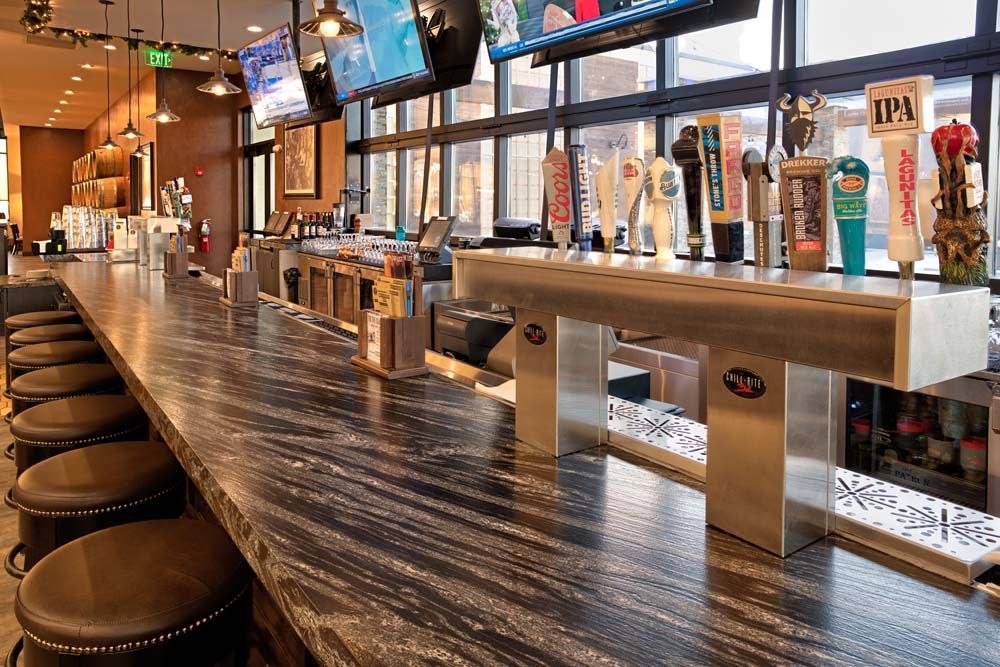A long bar with a lot of beer taps on it in a restaurant.