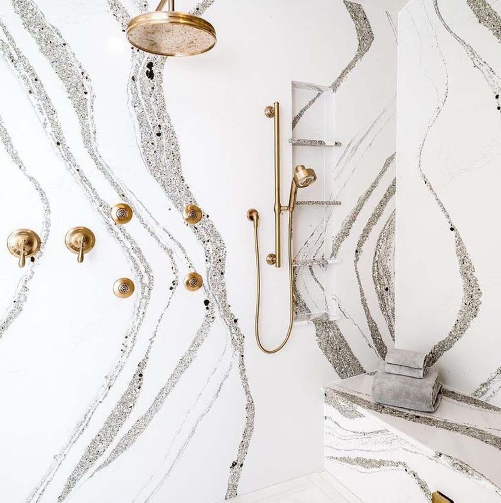 A bathroom with a shower and a marble wall.