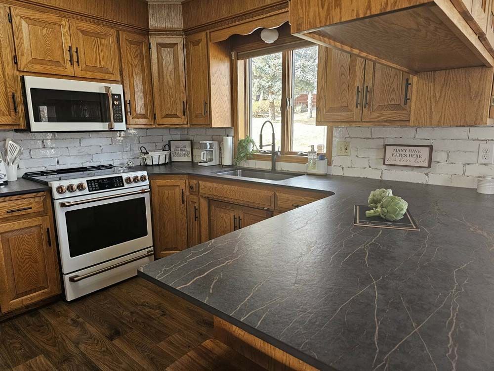 A kitchen with wooden cabinets , a stove , a microwave , and a sink.
