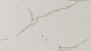 A close up of a white marble counter top with blue spots on it.