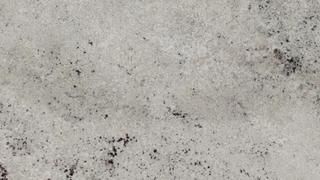 A close up of a white granite counter top with black spots.