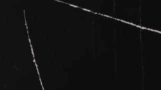 A close up of a black marble counter top with white veins.