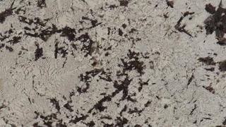 A close up of a white granite counter top with black spots.