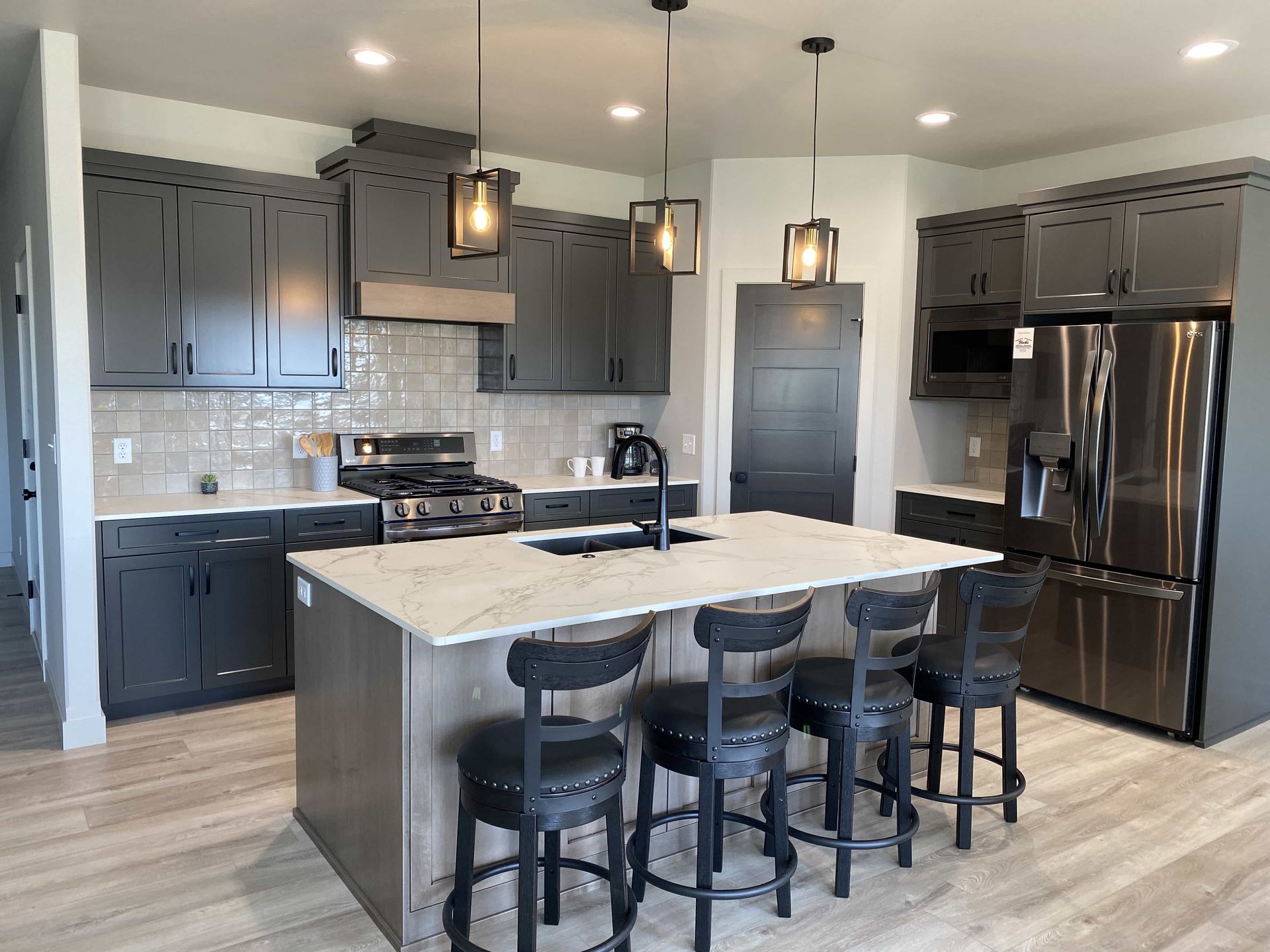A kitchen with gray cabinets , stainless steel appliances , and a large island.