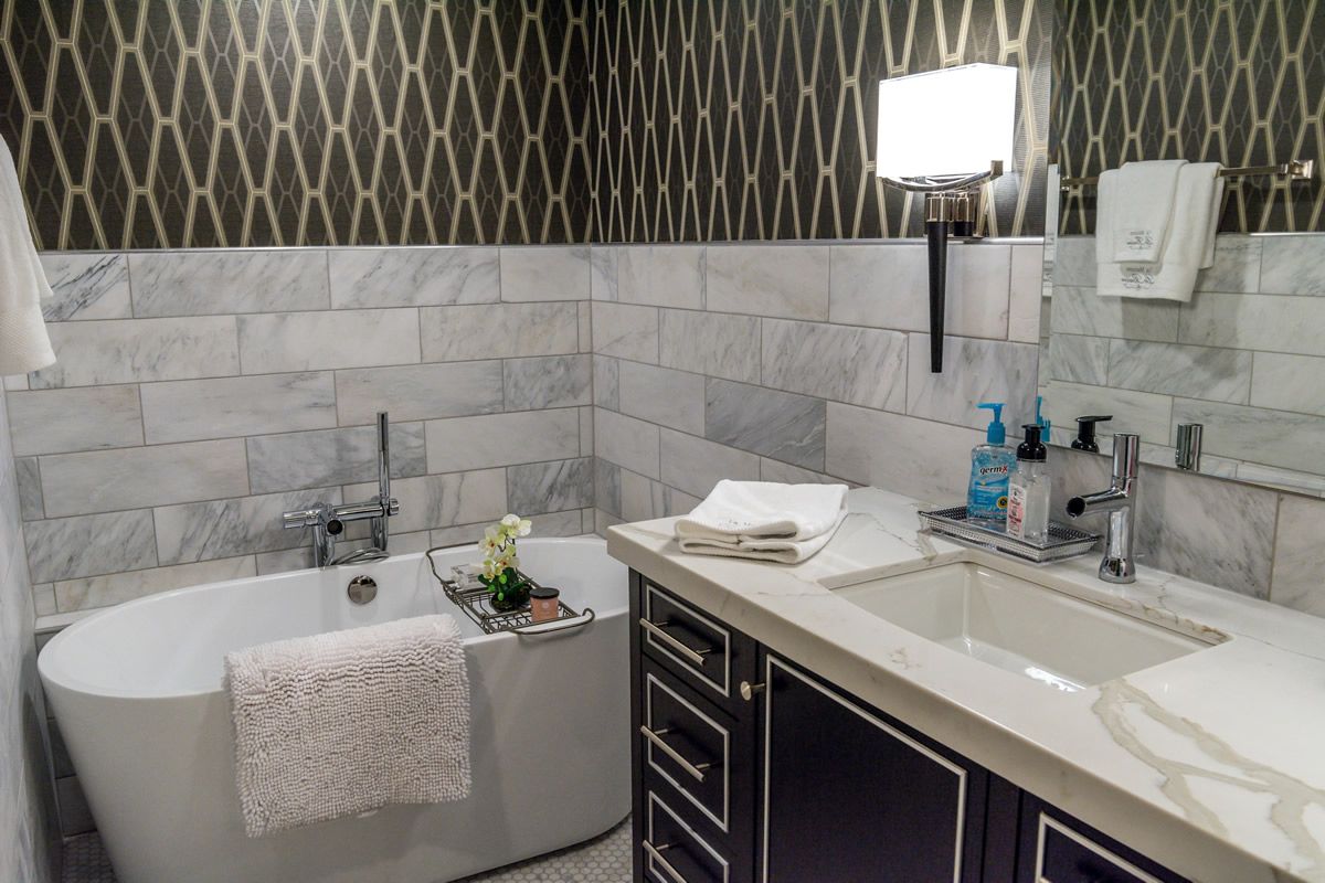 A bathroom with a tub , sink and mirror.