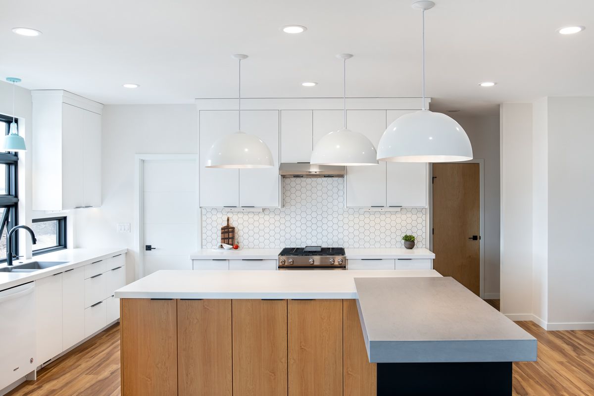 A kitchen with white cabinets , wooden cabinets and a large island.