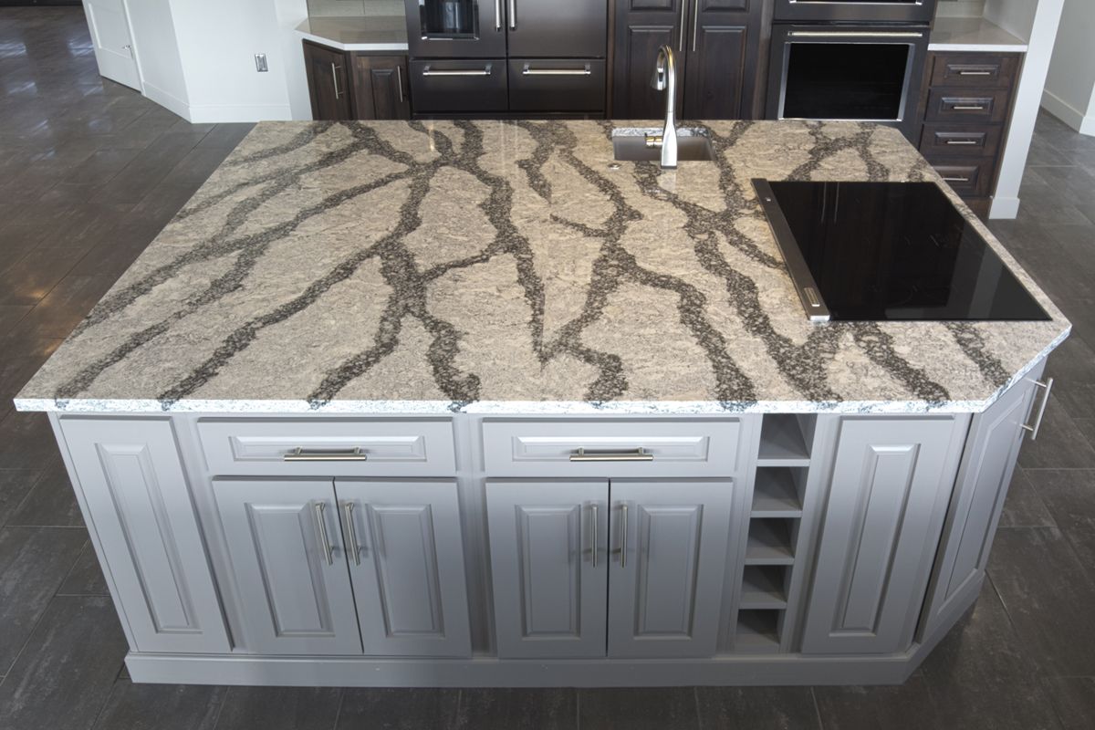 A kitchen island with a granite counter top and a stove top oven.