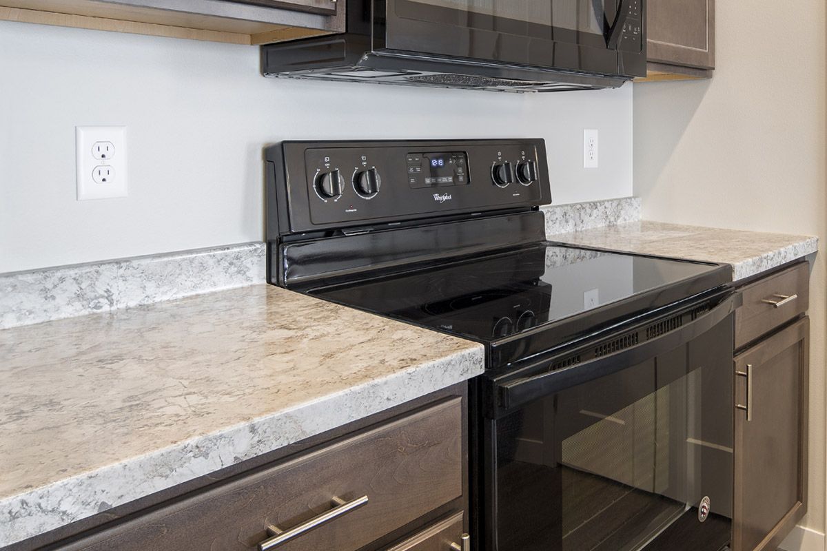 A kitchen with a stove , oven , microwave and granite counter tops.