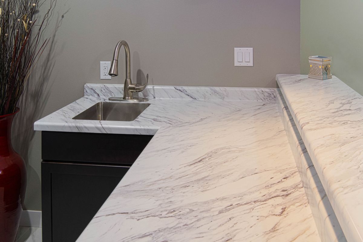 A kitchen with a sink and a marble counter top.