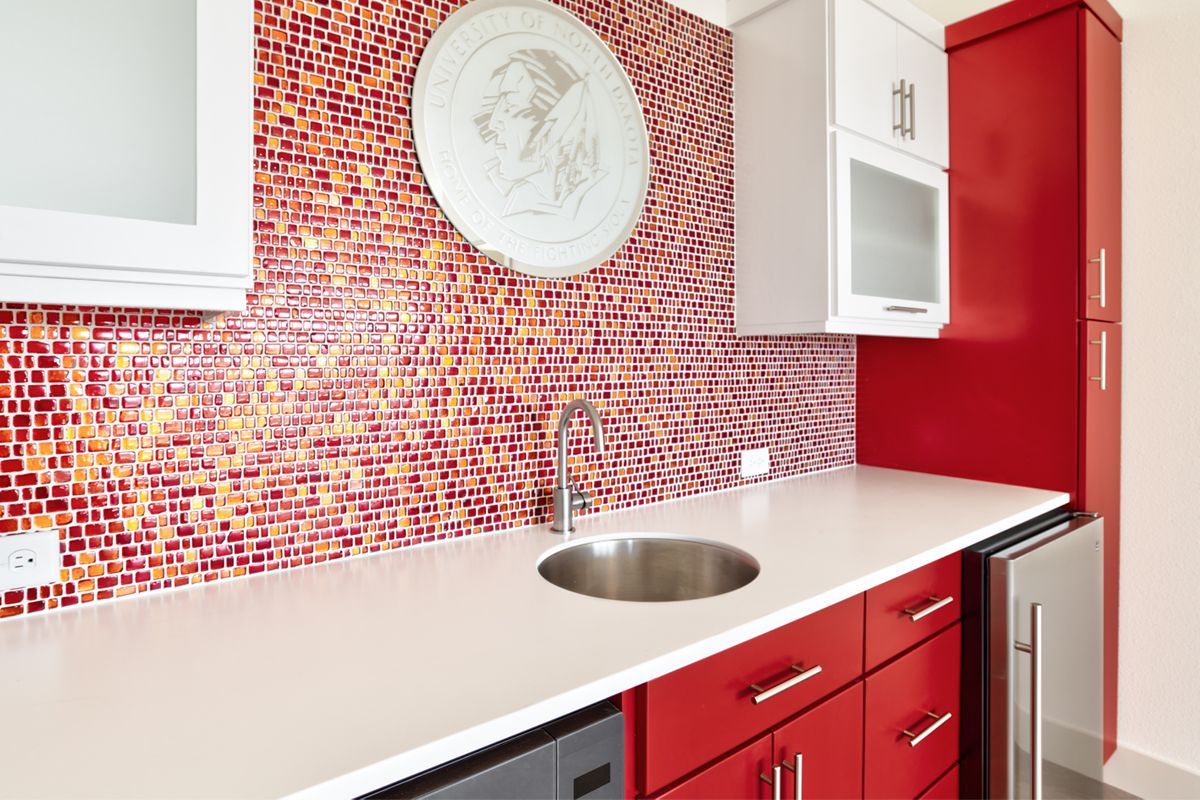 A kitchen with red cabinets and a stainless steel sink