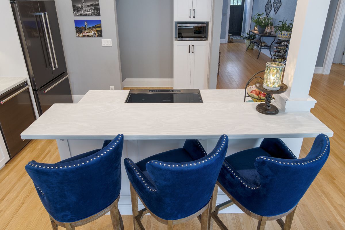 A kitchen with three blue bar stools and a white counter top.