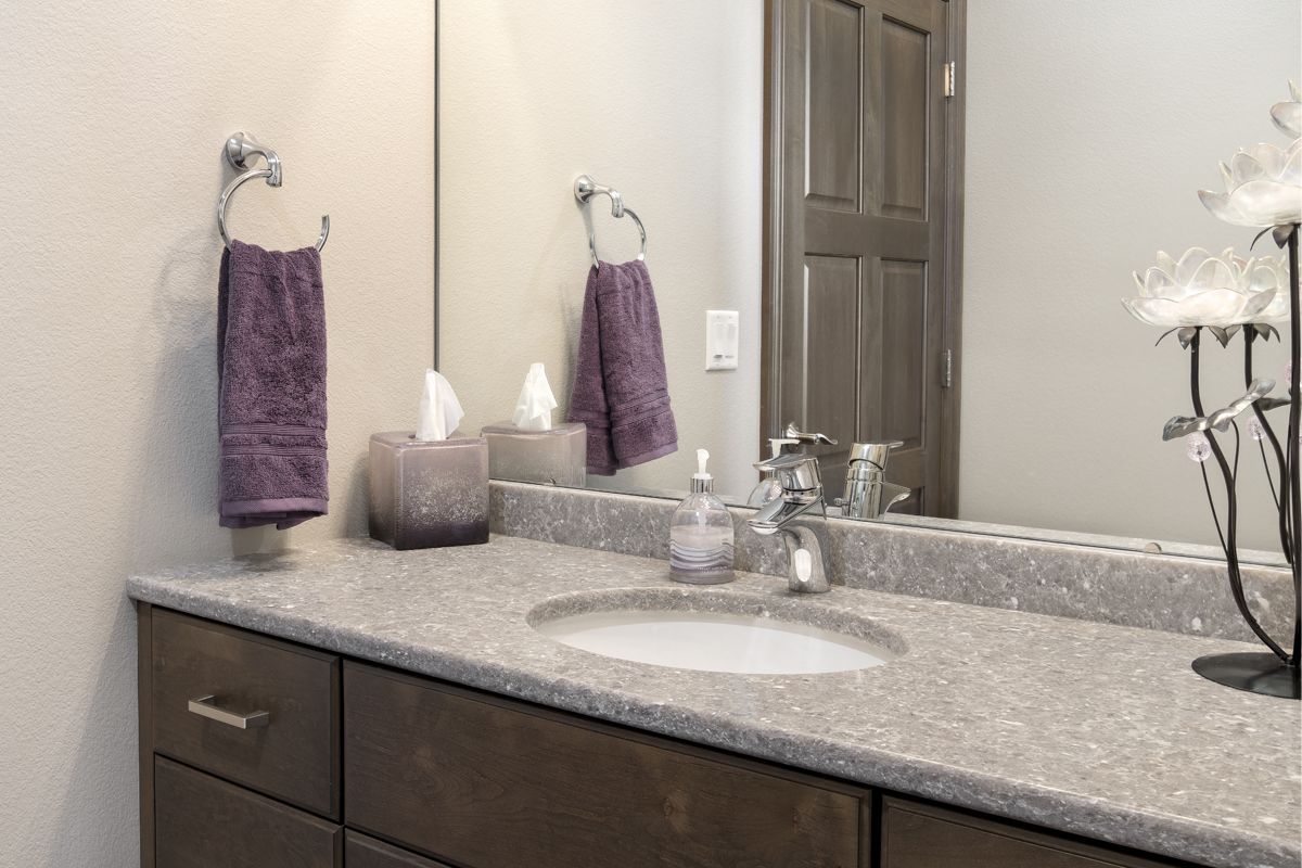 A bathroom with a sink , mirror and purple towels hanging on the wall.