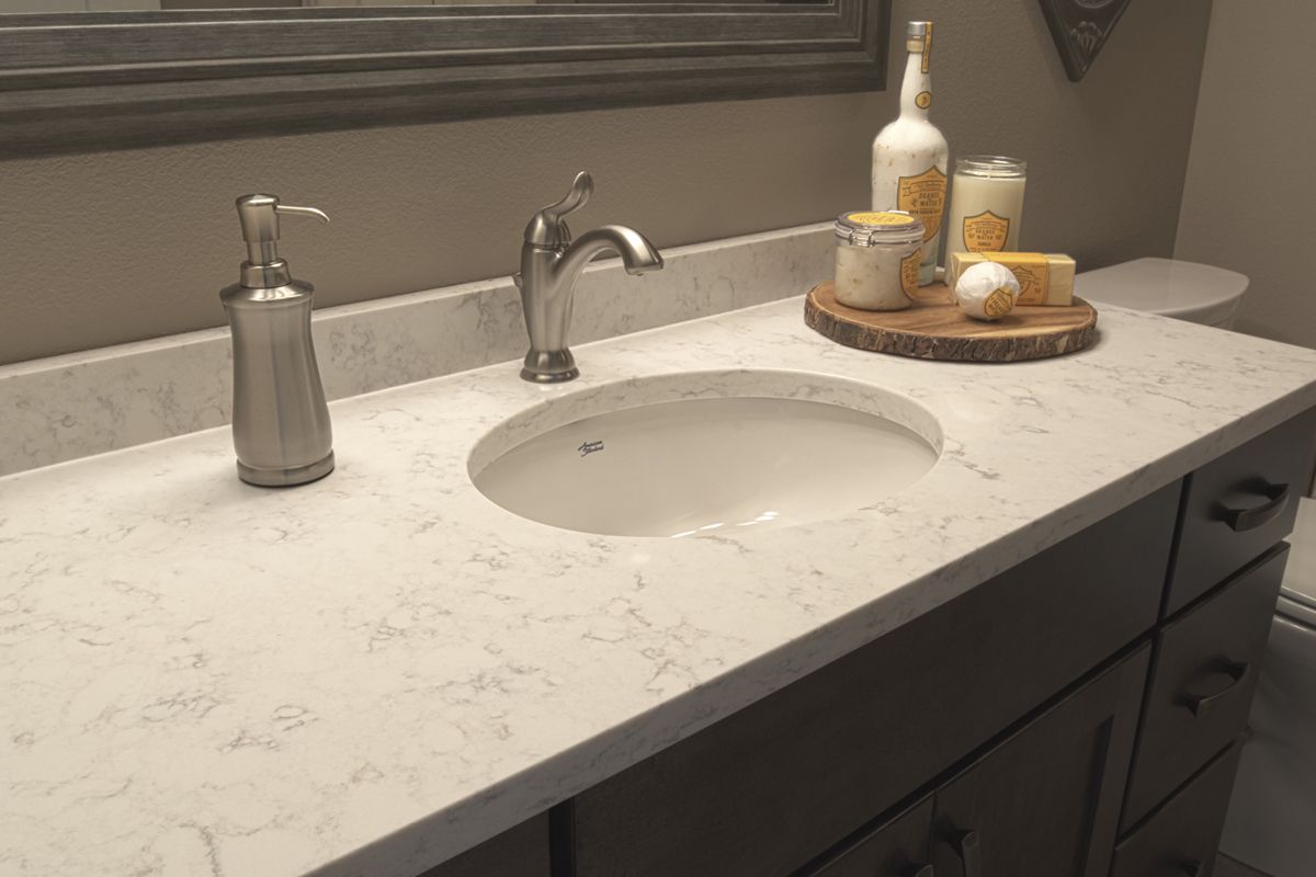 A bathroom vanity with a sink , faucet , and soap dispenser.