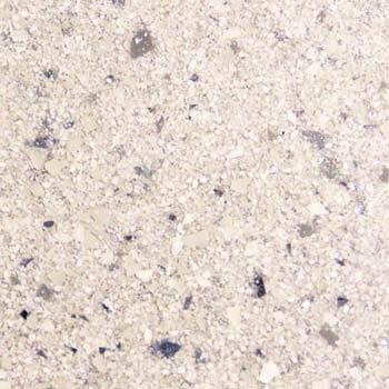 A close up of a white granite counter top with black spots.