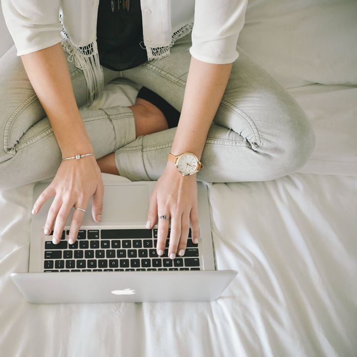 A woman wearing a watch is typing on a laptop