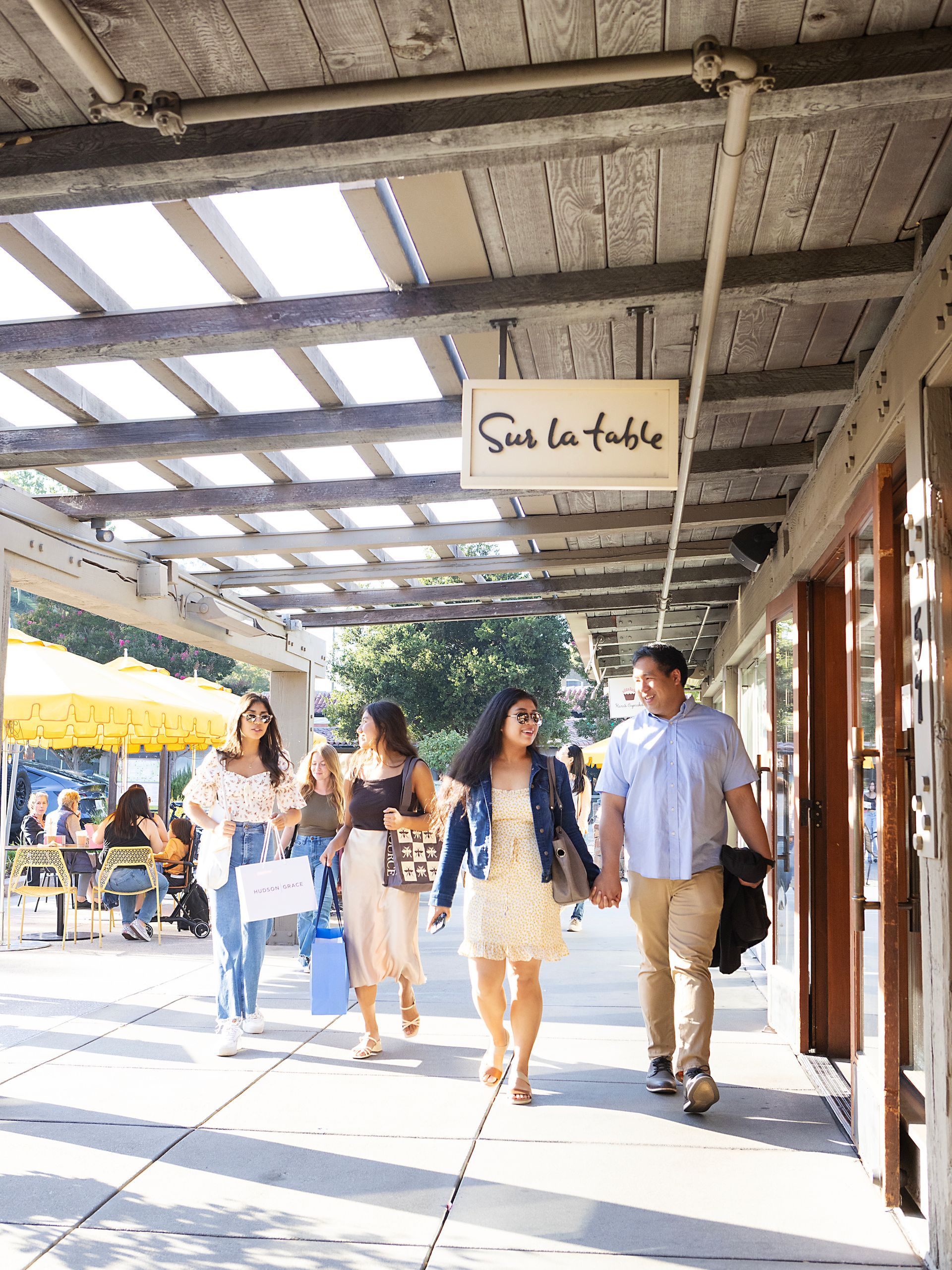A group of people are walking down a sidewalk holding hands.
