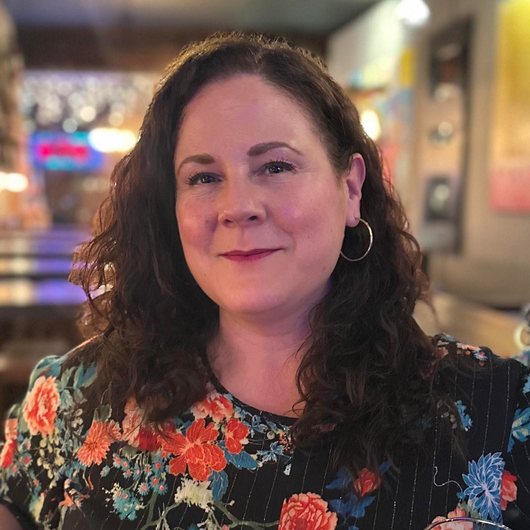 A woman wearing sunglasses and a pearl necklace is standing in front of a shower curtain.