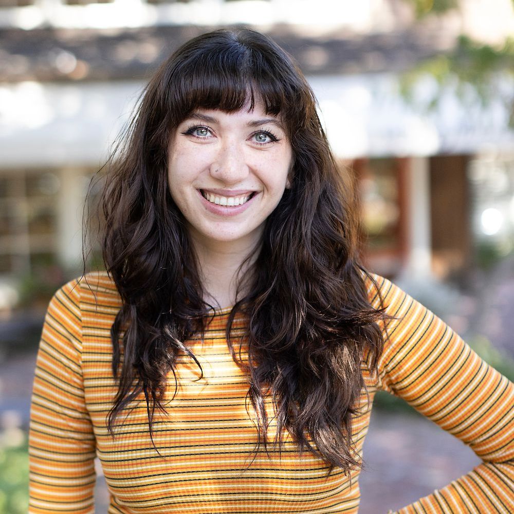 A woman wearing a yellow striped shirt is smiling for the camera.