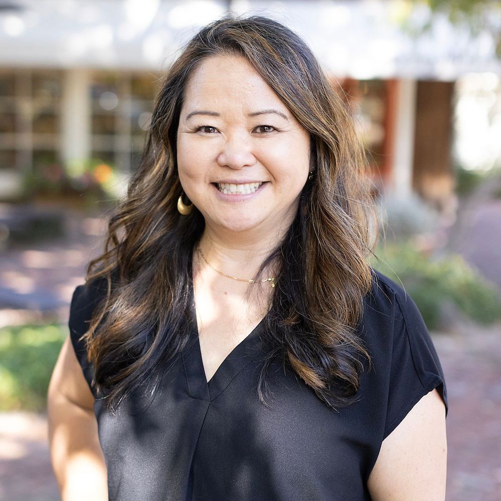 A woman in a black shirt is smiling for the camera.