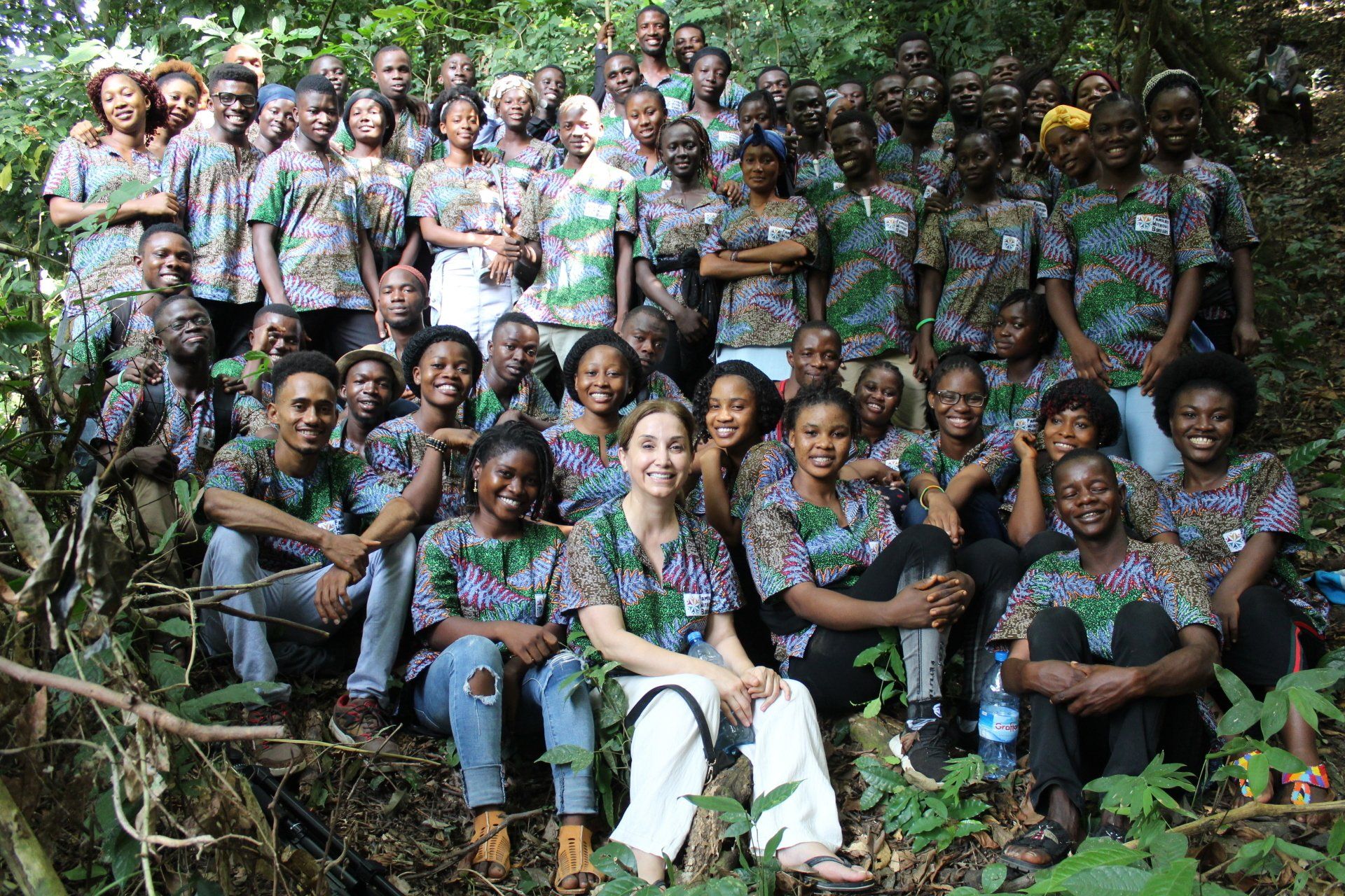 A large group of people are posing for a picture in the woods.
