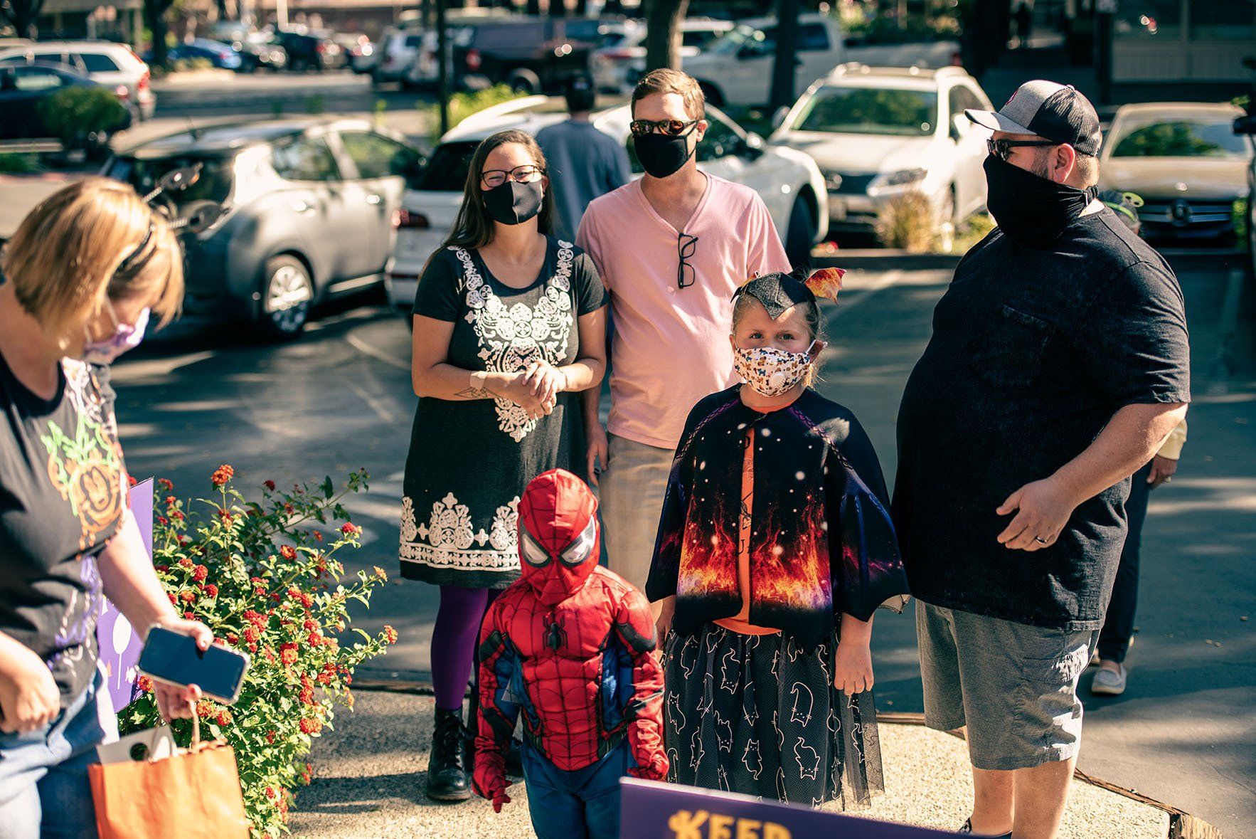 A group of people wearing face masks are standing in a parking lot.