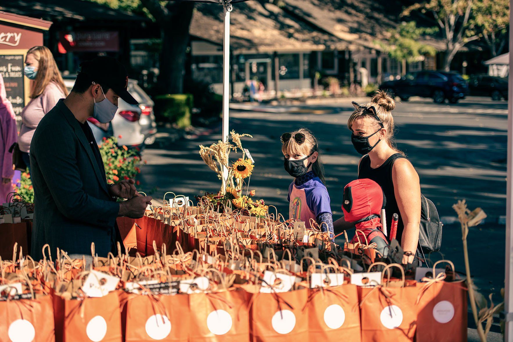 A group of people wearing face masks are standing around a table.