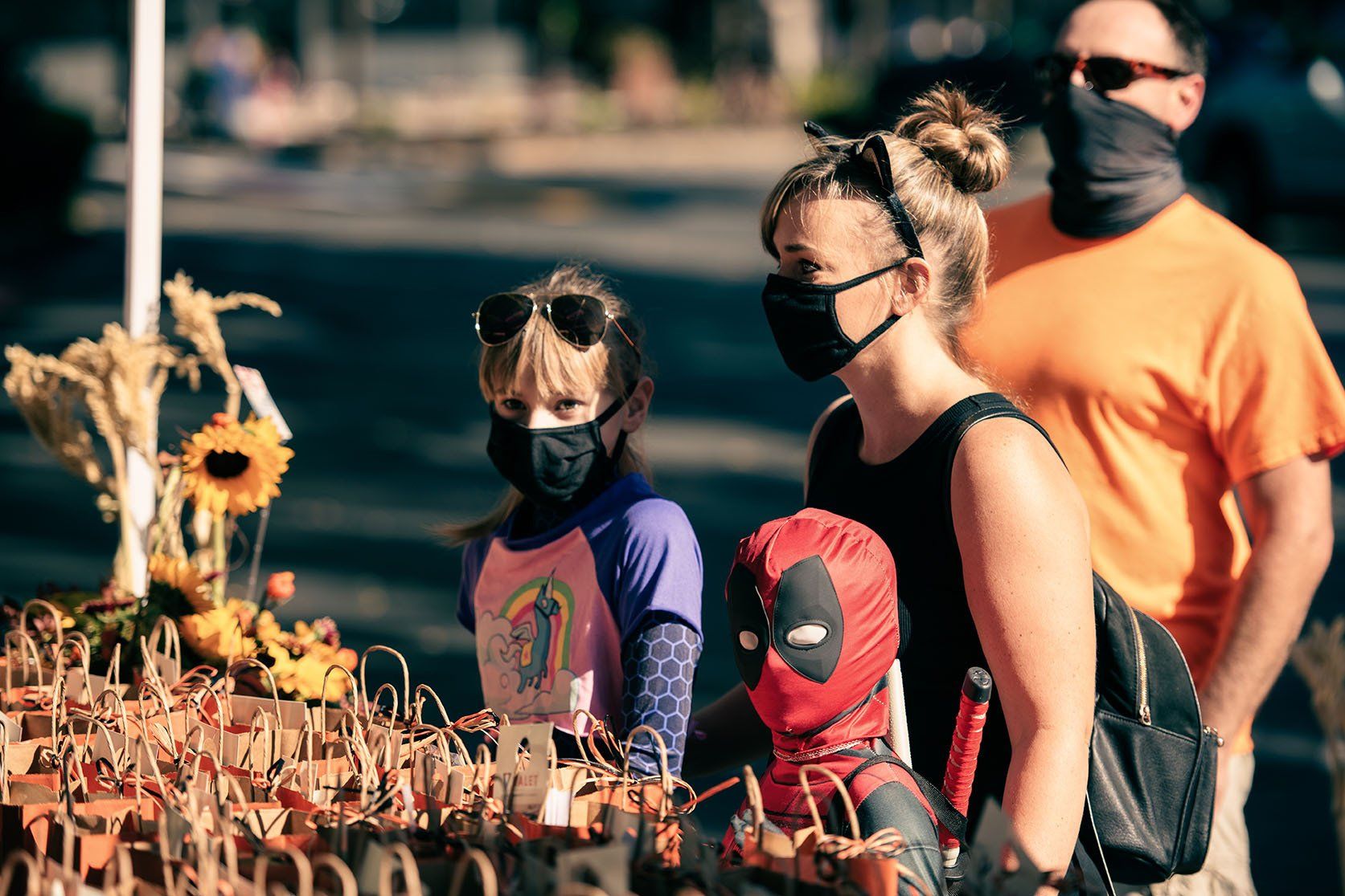 A group of people wearing face masks are standing around a table.
