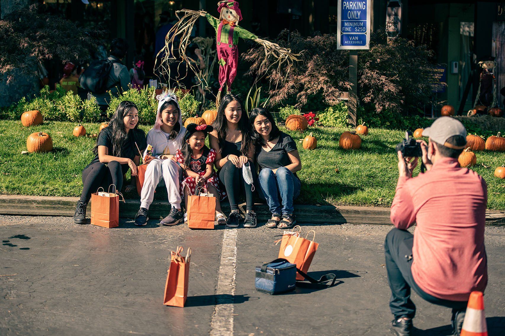 A man is taking a picture of a group of people sitting on the side of the road.