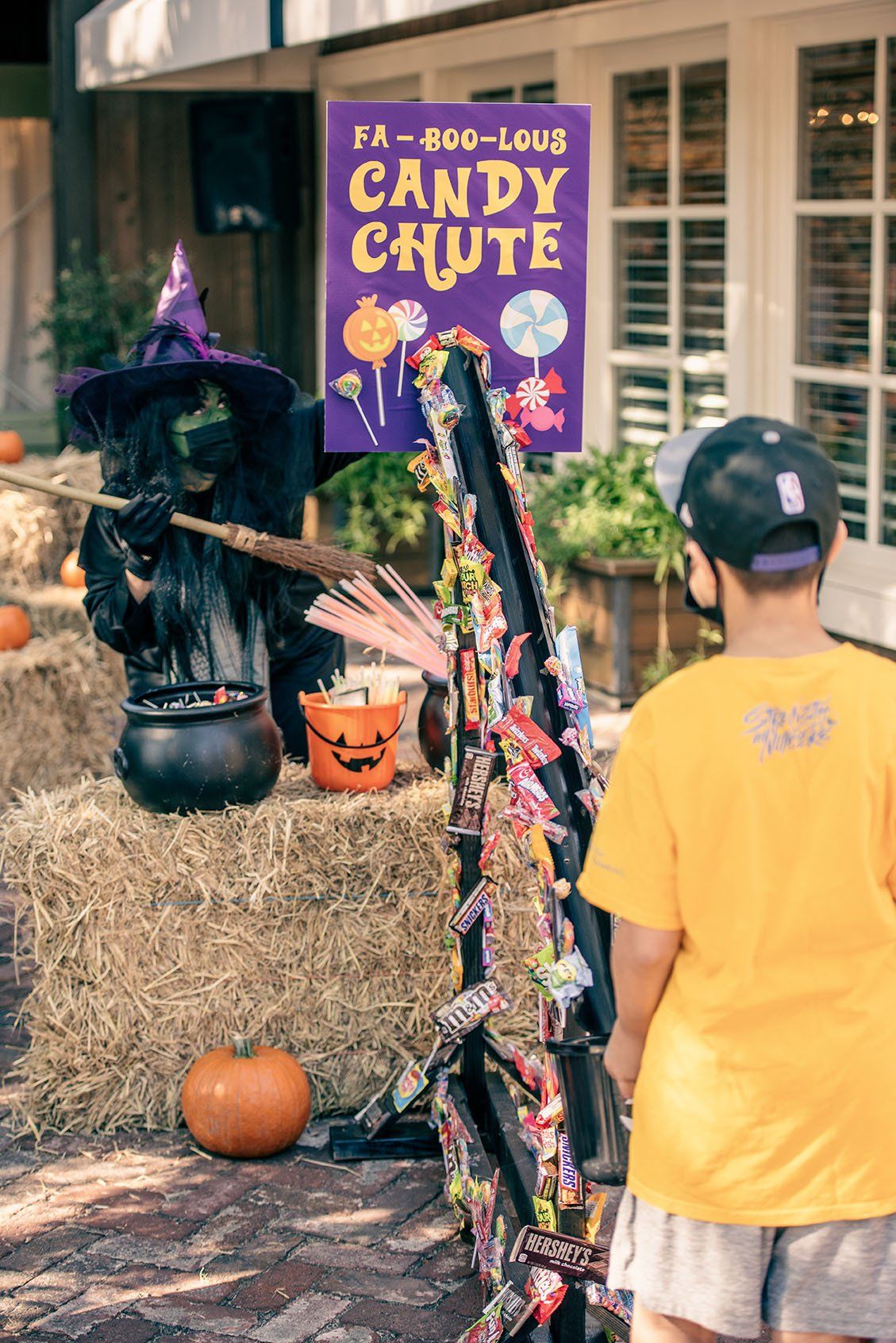 A young boy is standing in front of a candy chute.