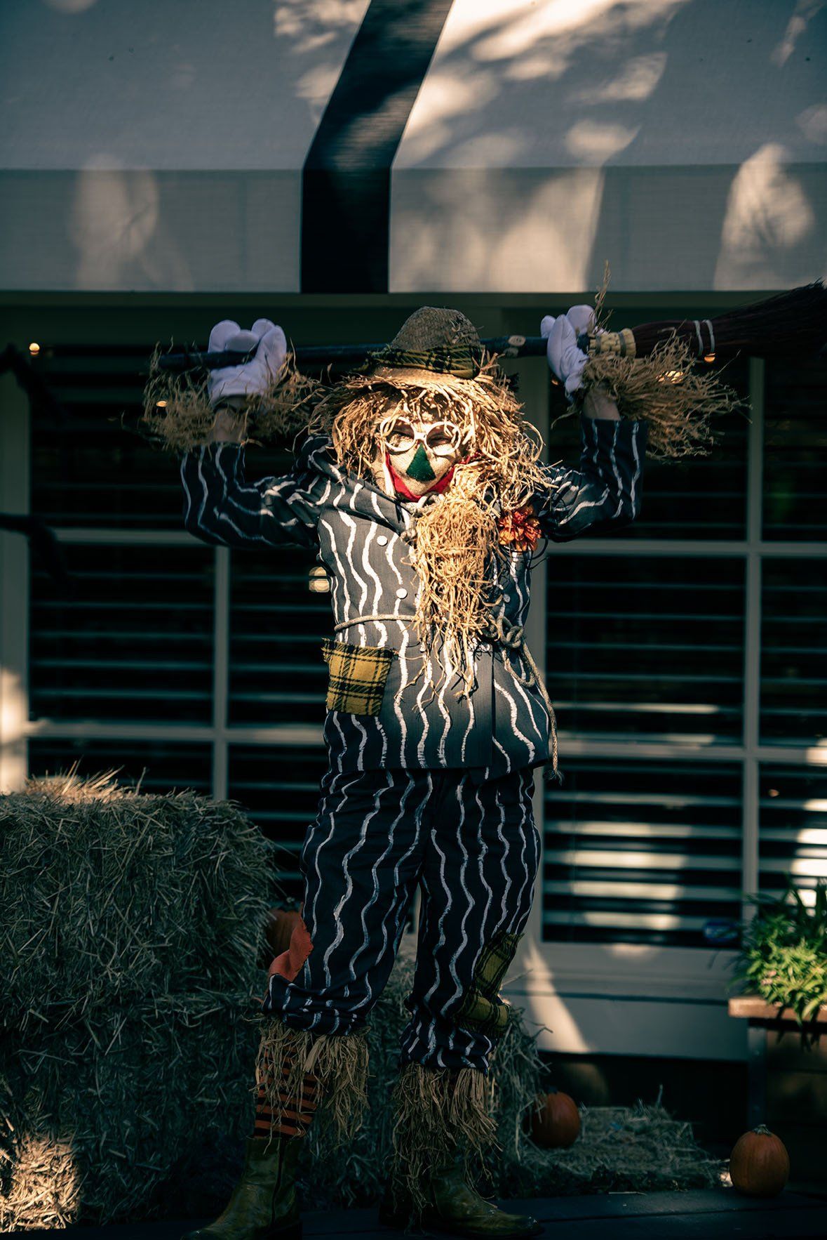 A scarecrow is standing next to a bale of hay.