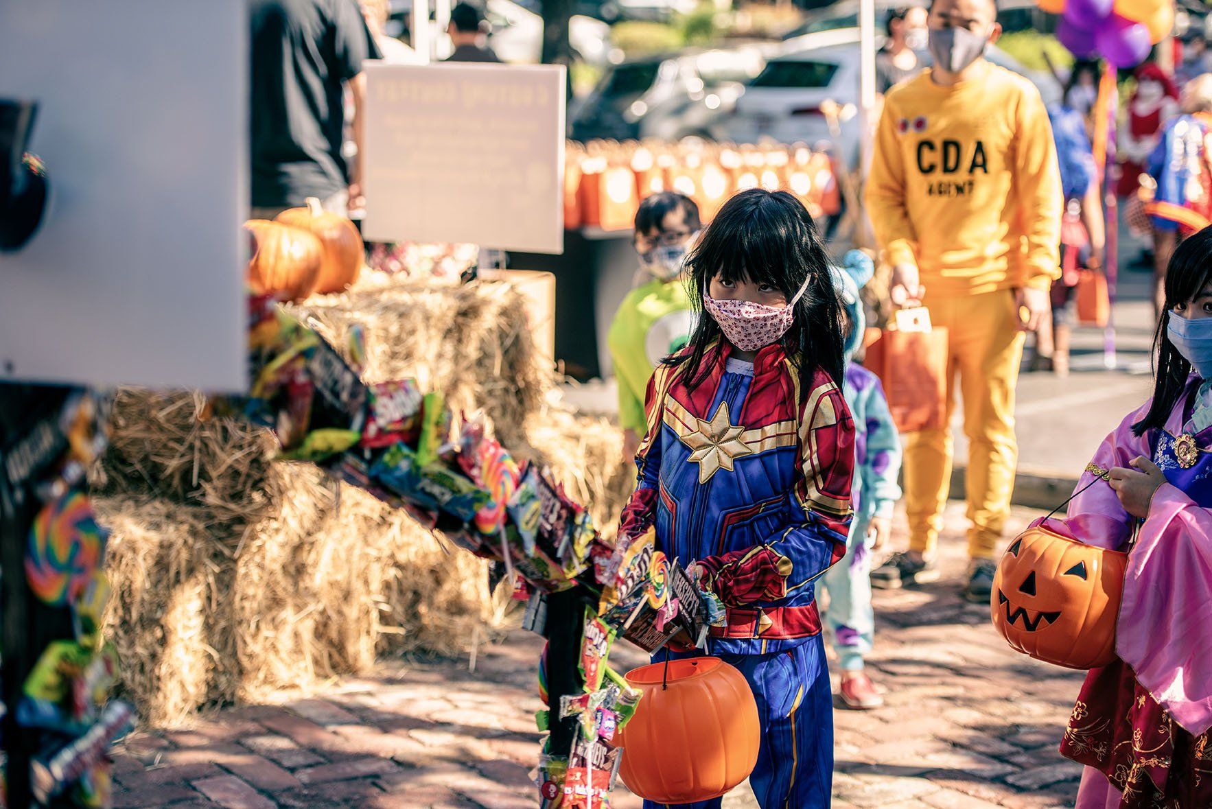 A group of children dressed in costumes are trick or treating.