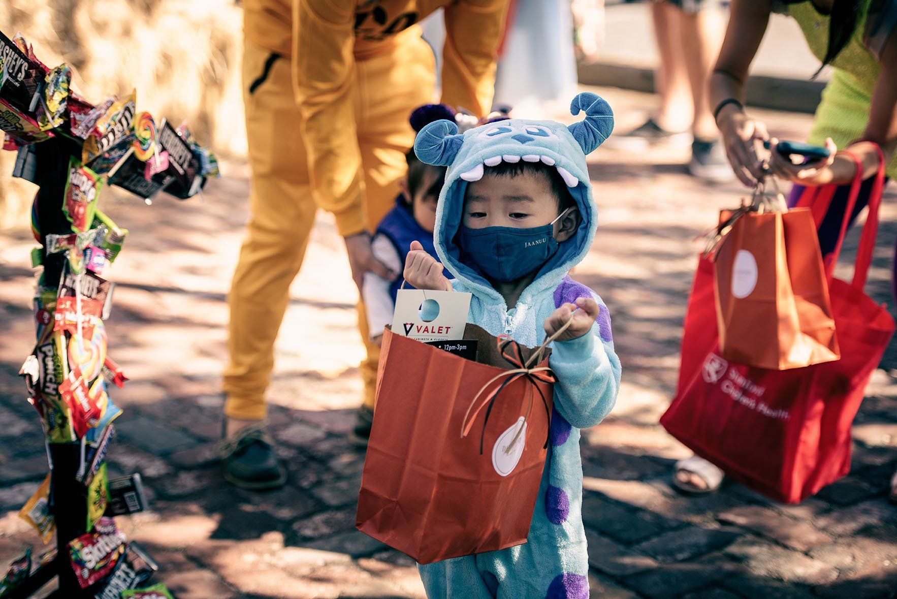 A little boy in a monster costume is holding a bag of candy.