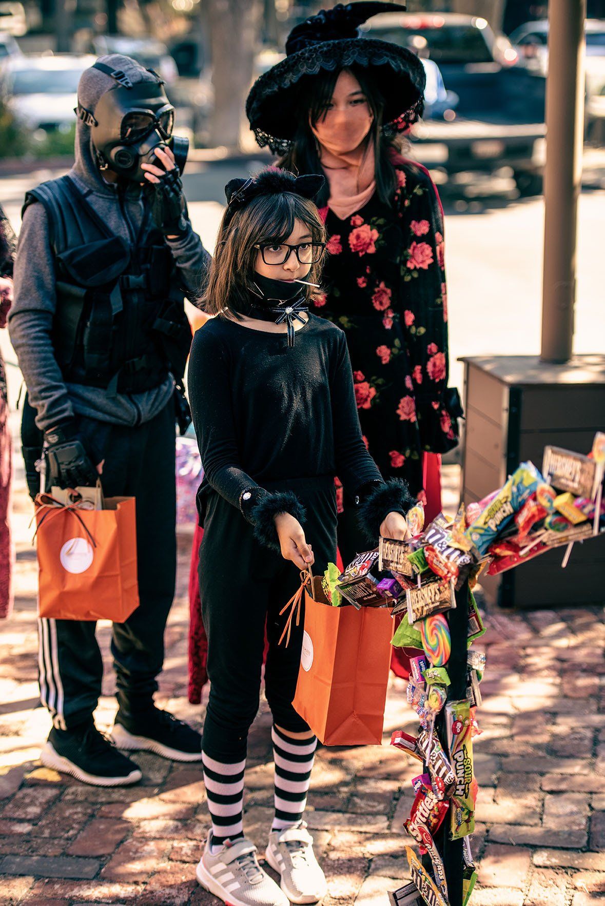 A group of people in halloween costumes are standing next to each other on a sidewalk.