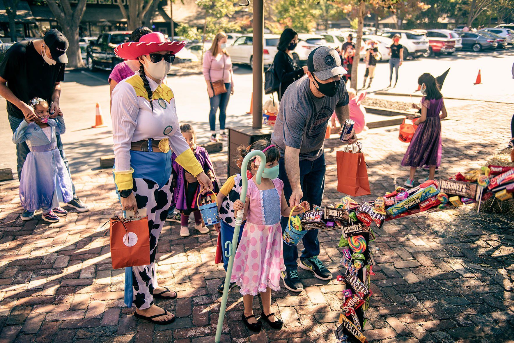 A group of people in costumes are standing on a brick sidewalk.