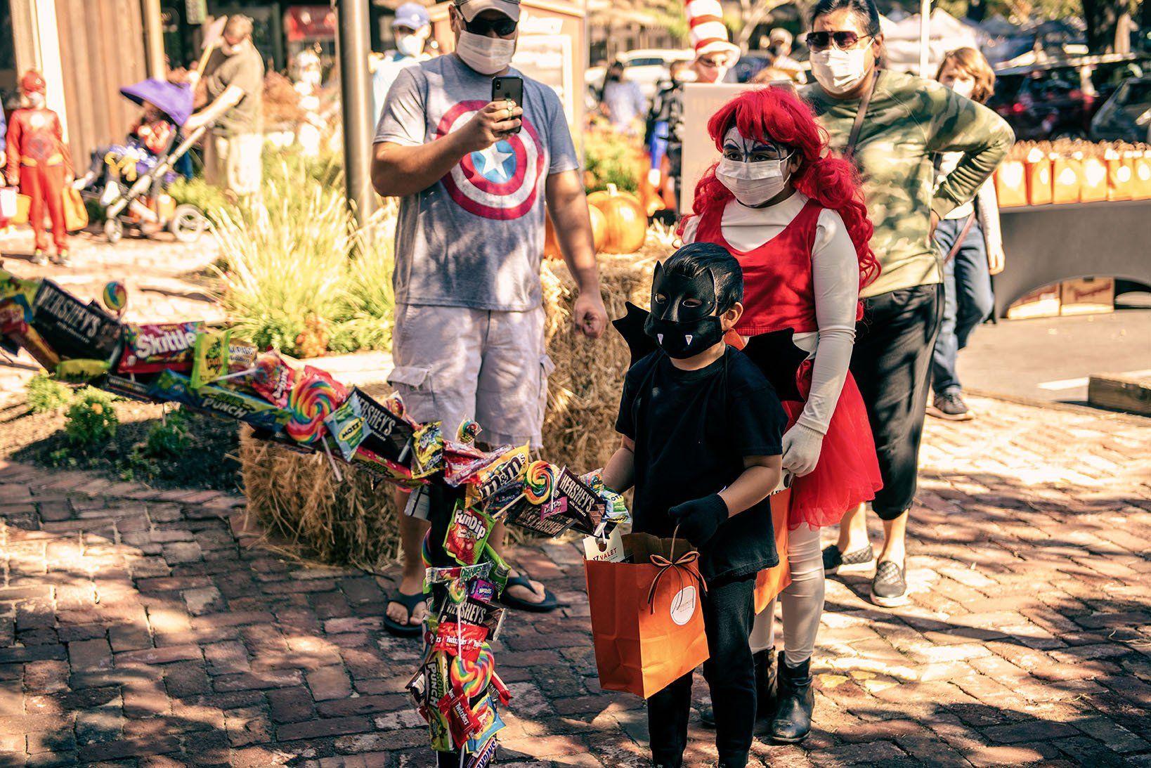 A group of people wearing face masks are walking down a sidewalk.