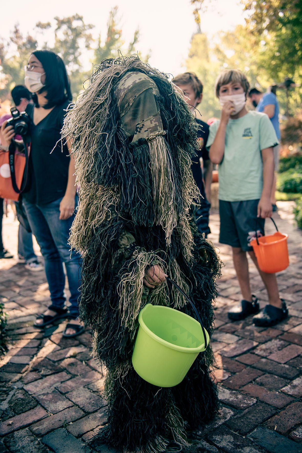 A person in a costume is holding a green bucket.