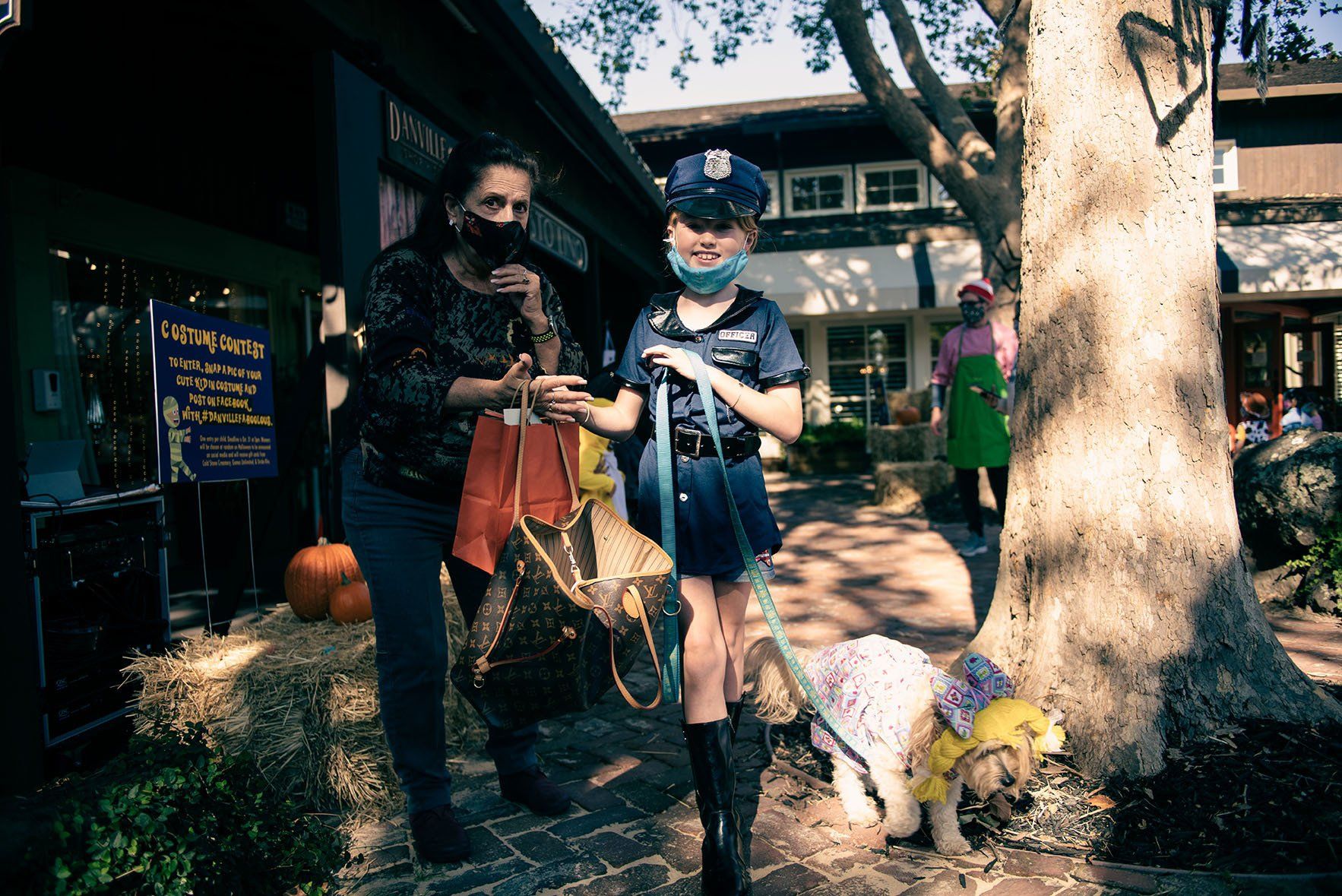 A girl dressed as a police officer is walking a dog.