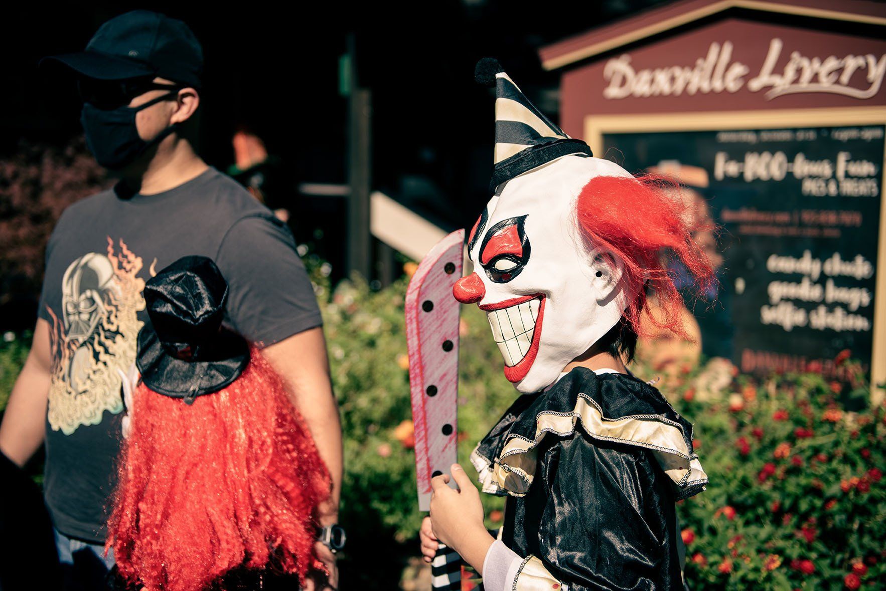 A man wearing a mask and a child in a clown costume