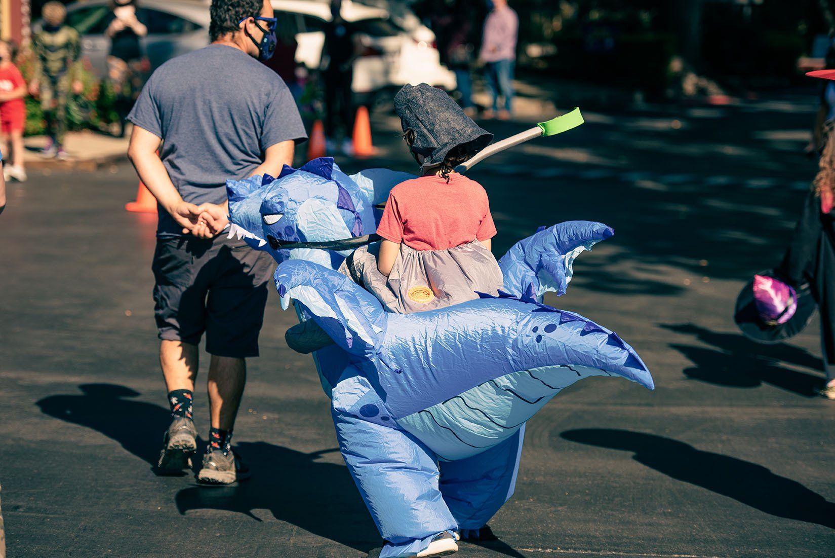 A man is carrying a child in an inflatable whale costume.
