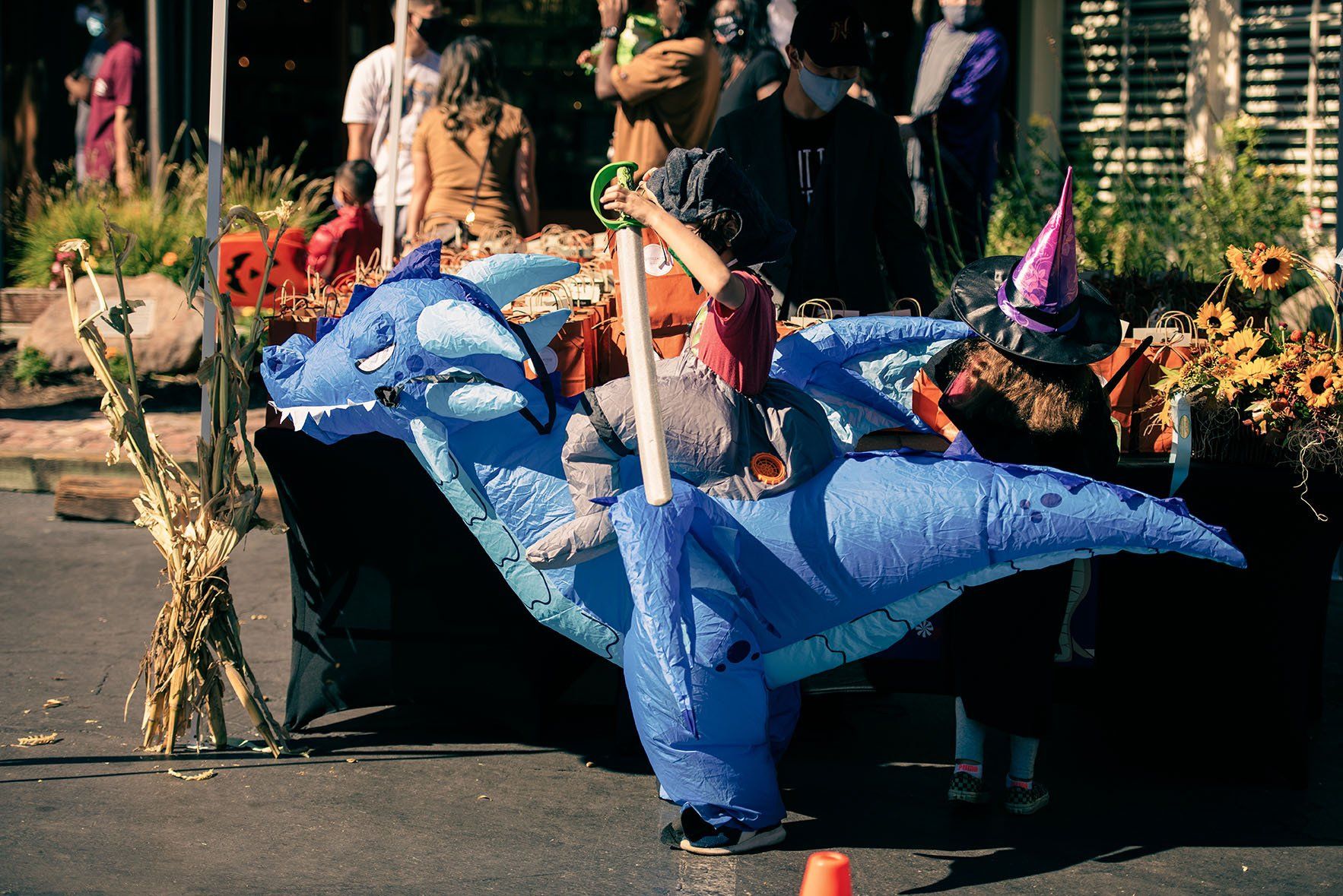 A child is riding on the back of a blue inflatable dinosaur.
