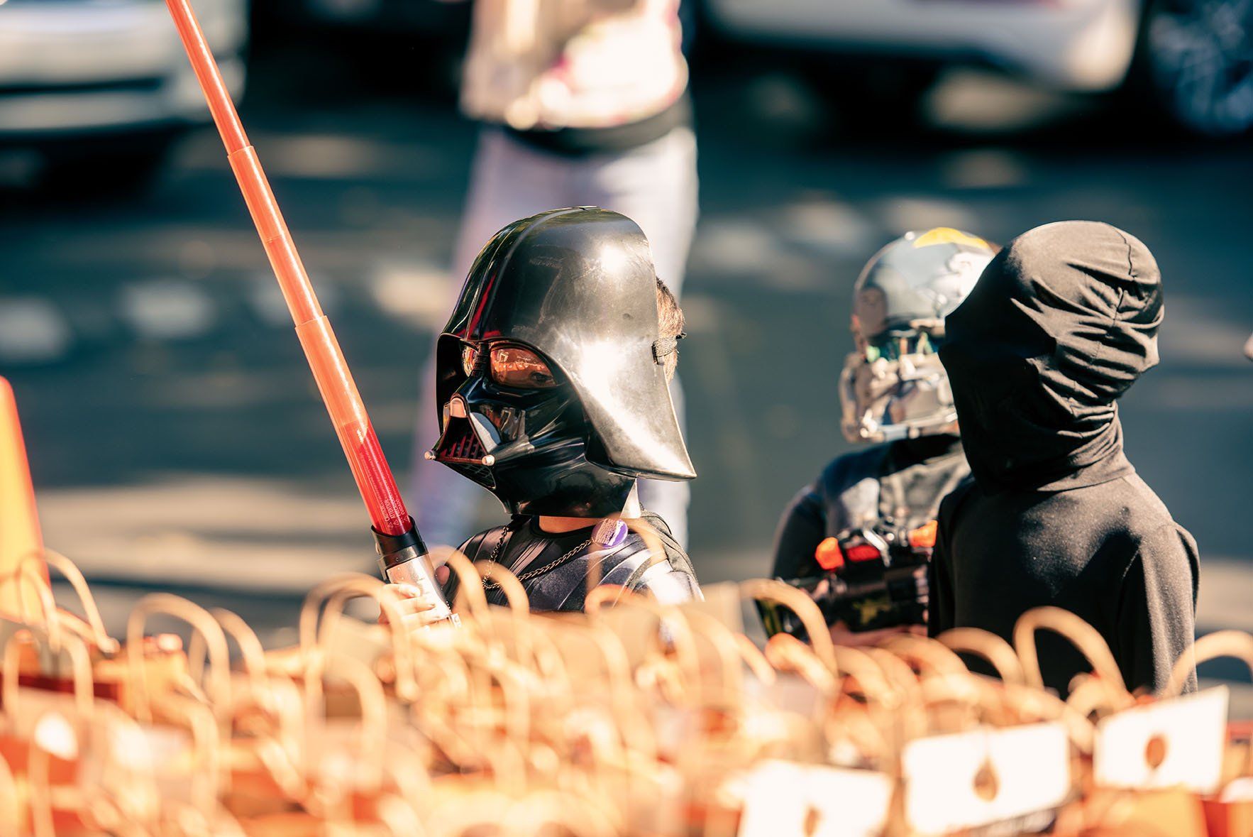 A boy dressed as darth vader is holding a light saber.
