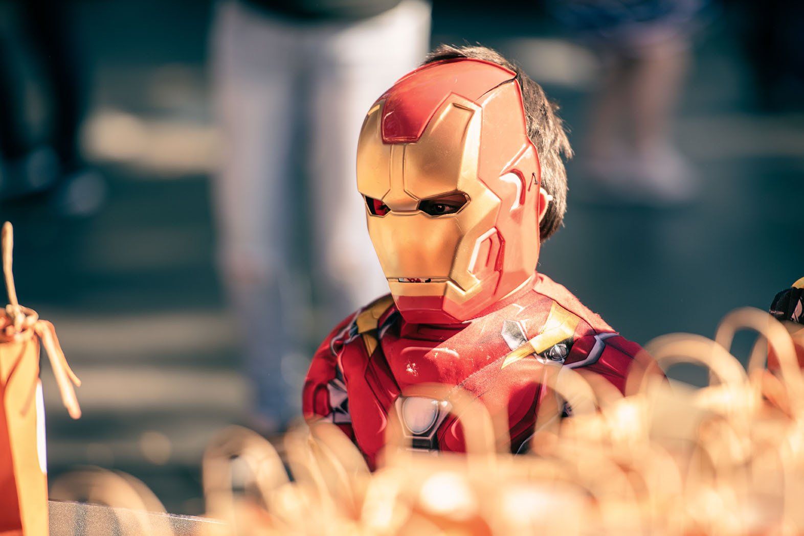 A young boy is wearing a iron man costume and mask.