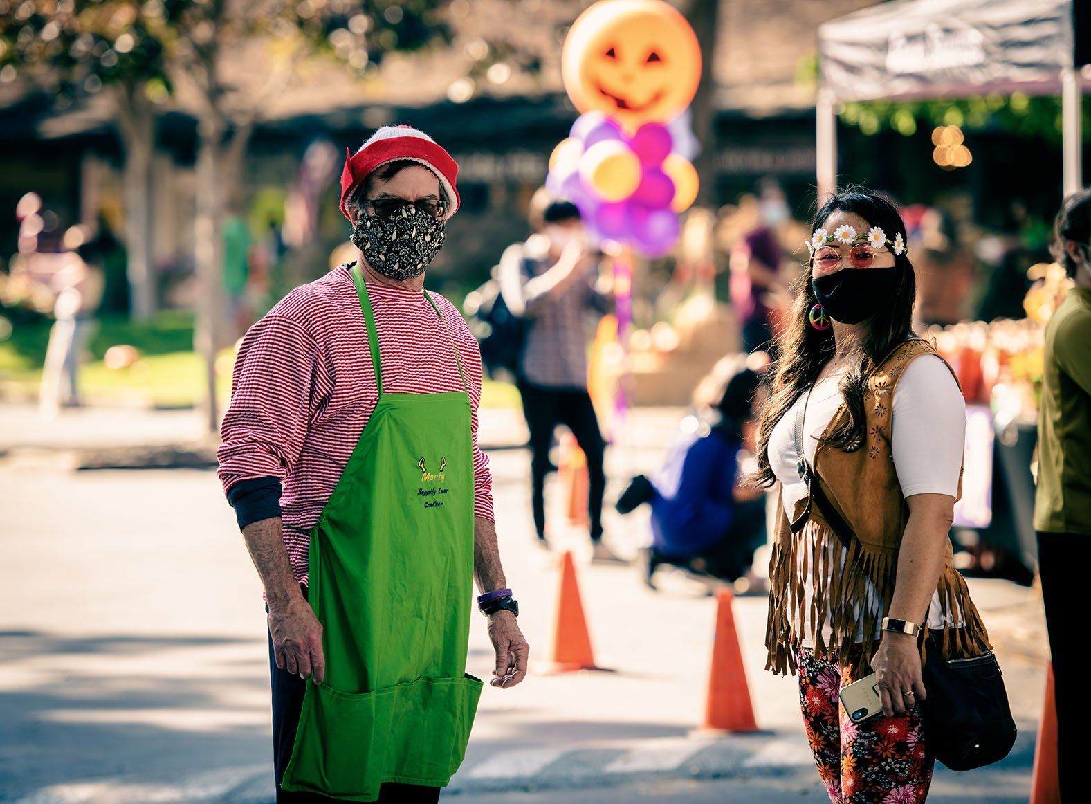A man and a woman wearing masks are standing next to each other on a street.
